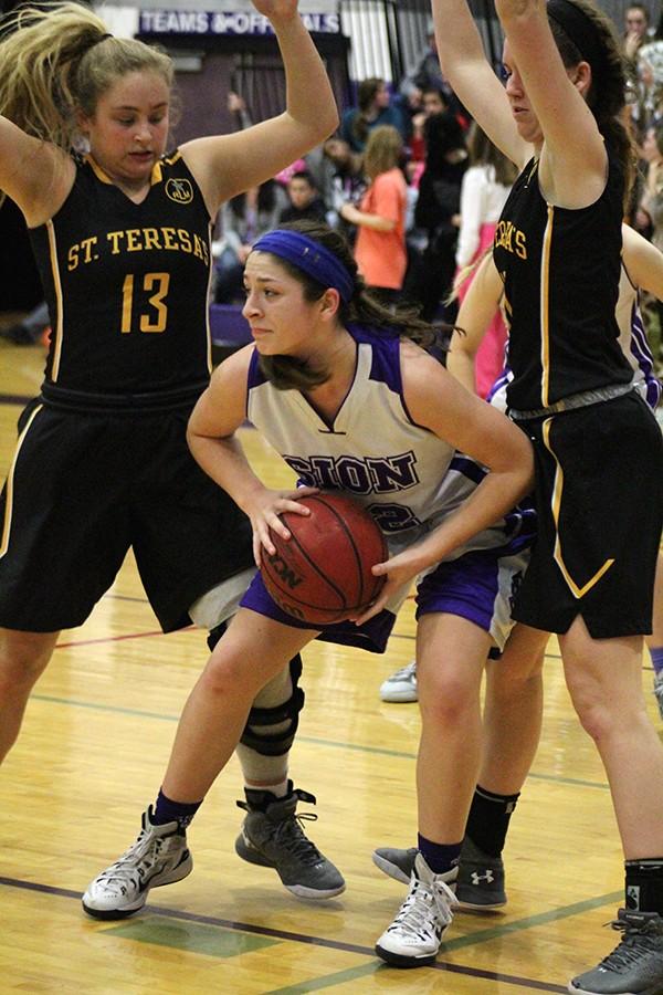 Sophomore Sarah Totta looks for a pass while trapped under the basket by St. Teresa's seniors Kathleen Herrington and Grace Kitts. Varsity Basketball lost 40-56 in the Jan. 29 game. 