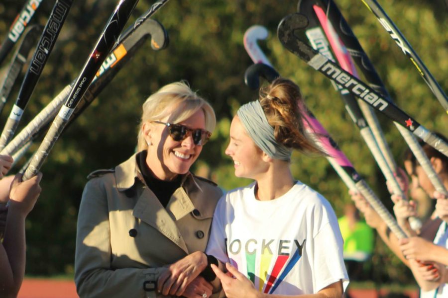 While walking through an "honor guard" of field hockey sticks, senior Grace Watkins is recognized at her last field hockey home game Oct. 16 with her mom Heidi Peter. 
