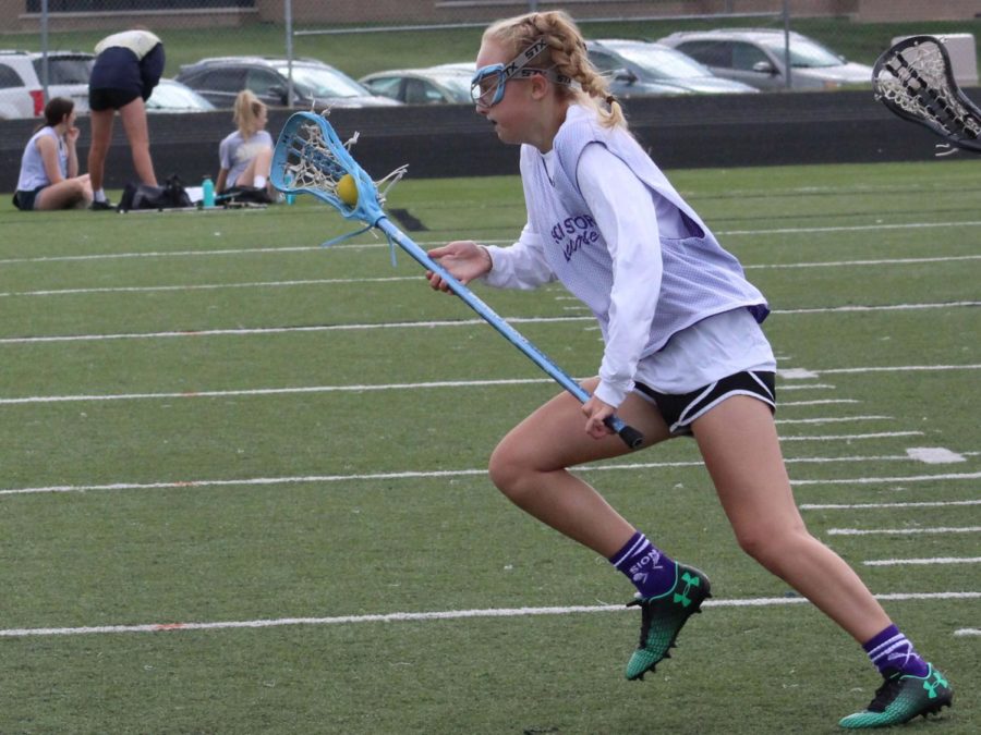 Junior Brie Bowes cradles the ball during a lacrosse fall ball game last season, Oct. 1, 2017. Fall ball gives the lacrosse team extra practice to prepare for the high school season in the spring.