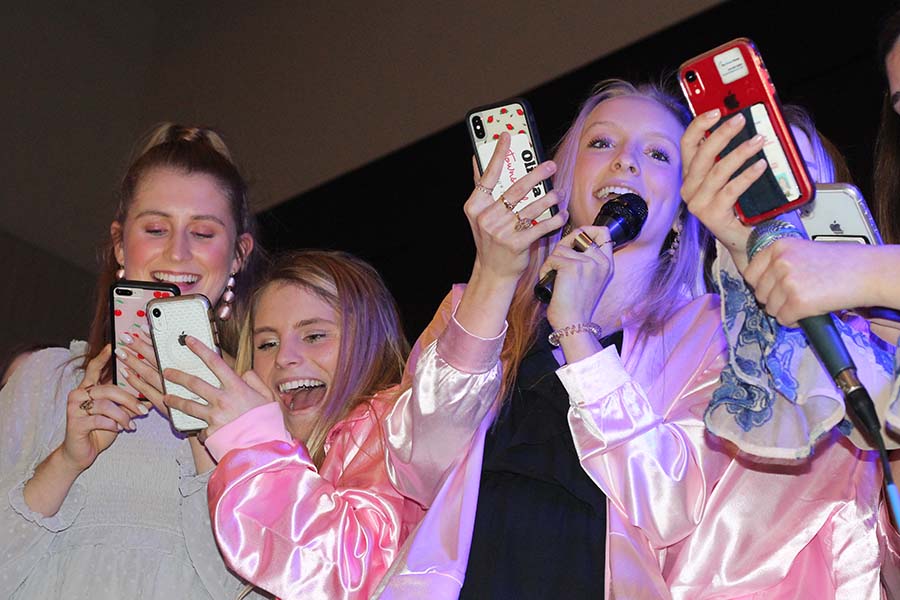 Seniors Kyleigh Smith, Phoebe Fridkin and Olivia Townsend read lyrics off their phones and sing Take Me Home Country Roads by John Denver to their fathers during the annual Father-Daughter dance Feb. 9.