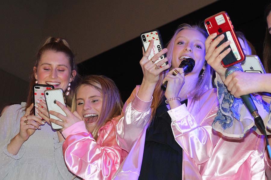 Seniors Kyleigh Smith, Phoebe Fridkin and Olivia Townsend read lyrics off their phones and sing "Take Me Home Country Roads" by John Denver to their fathers during the annual Father-Daughter dance Feb. 9.