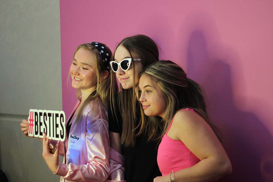 Freshmen Shelby Beck, Gabel Whittaker and Katie Kasper pose with props for the photo booth during the annual Father-Daughter dance Feb. 9. This years theme was Pink Ladies.