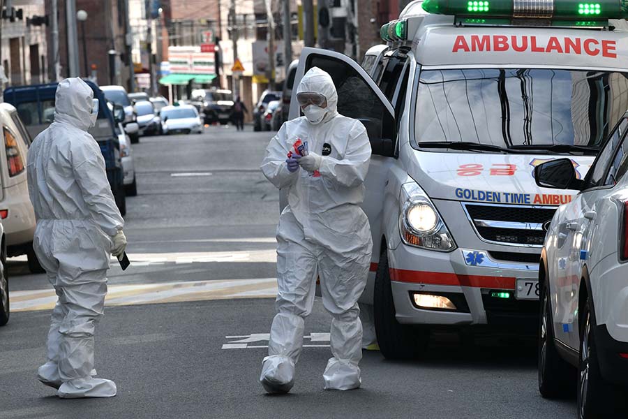 South Korean medical workers wearing protective gear carry samples as they visit a residence of people with suspected symptoms of the COVID-19 coronavirus, near the Daegu branch of the Shincheonji Church of Jesus in Daegu on Feb. 27.
