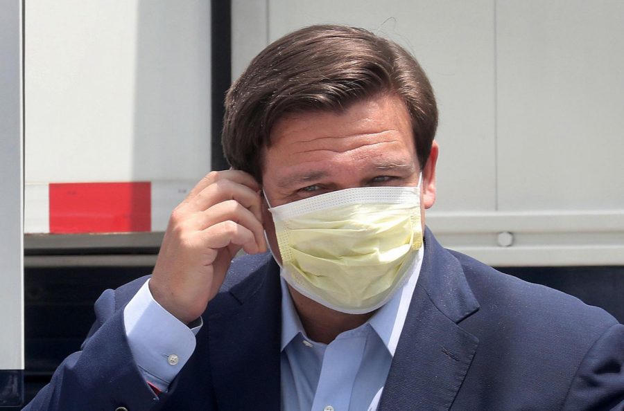 Florida Gov. Ron DeSantis removes his face mask as he prepares for a news conference on April 8, 2020 at the Miami Beach Convention Center, which is being converted into an alternate care facility. 