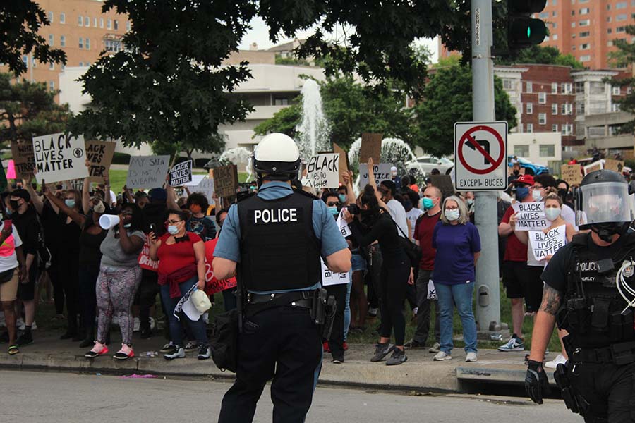 A police officer faces a crowd of people protesting police brutality and advocating for the Black Lives Matter movement in front of the J.C. Nichols Memorial Fountain on May 30. The protest was organized in response to the murders of two unarmed black citizens, George Floyd and Breonna Taylor, by the police. 