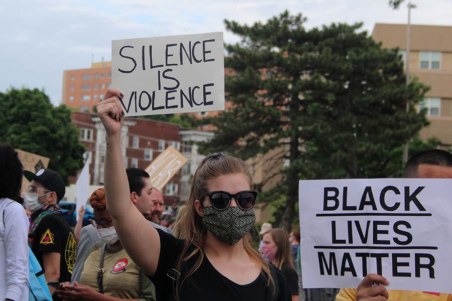 A protester wearing a mask holds up a sign reading Silence Is Violence at the Black Lives Matter protest at the Country Club Plaza on May 30. Attendees were strongly encouraged to wear face masks and follow social distance guidelines during the protest in order to limit the spread of COVID-19.