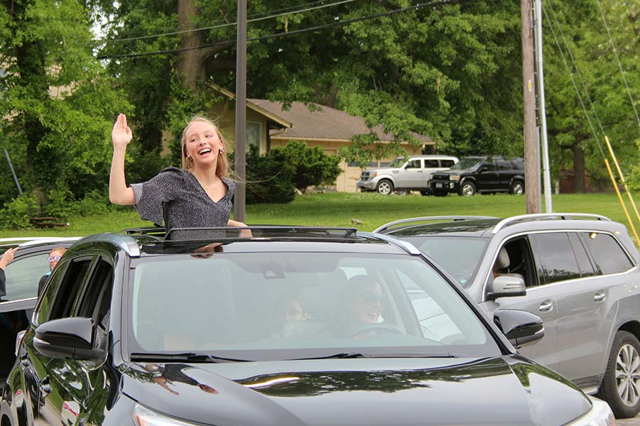 Senior Brie Bowes waves to her teachers during the graduation parade in the parking lot on May 21. 
