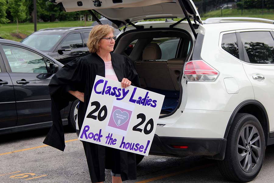 Assistant Principal for Student Life Fran Koehler watches the graduation parade and holds a sign in the parking lot on May 21.