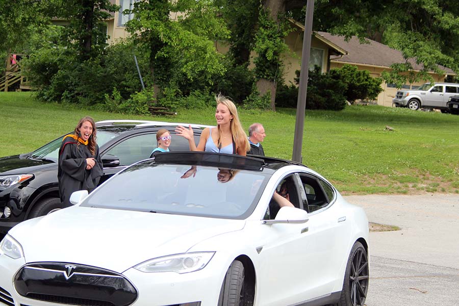 Senior Nina Trouvé waves to her teachers from her car during the graduation parade in the parking lot on May 21.