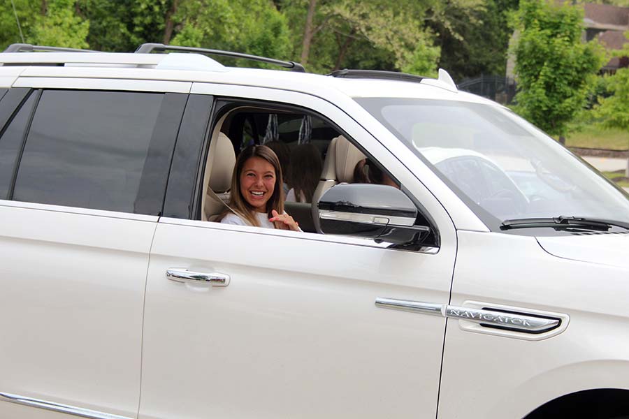 Senior Emily Rine laughs with her teachers from her car while celebrating the end of her senior year during the graduation parade in the parking lot on May 21.