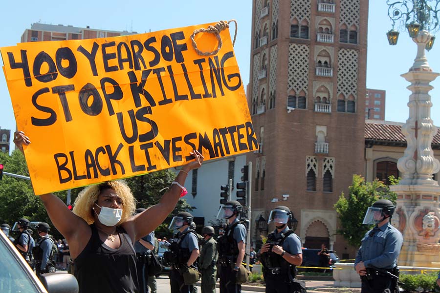 A protester holding a sign marches in front of the line of Kansas City Police officers during the protest against police brutality against black people at the Country Club Plaza on May 31.