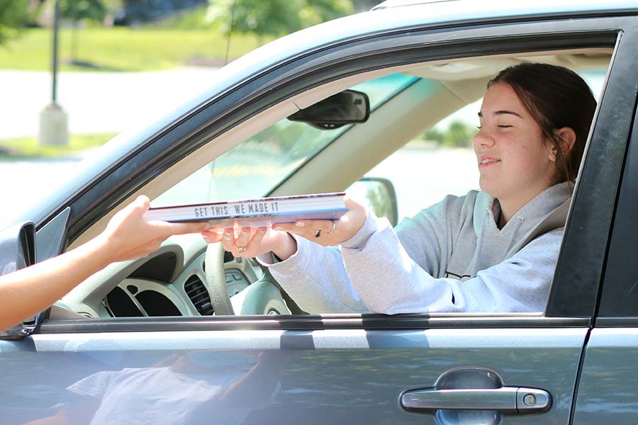 Sophia Angrisano, Class of 20 receives her copy of the yearbook from her car in the parking lot on Aug. 5. The theme of the yearbook is Get This.