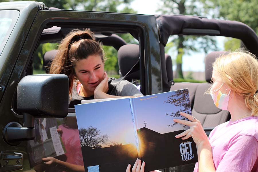 Reilly Jackoboice and Lily Henkle, Class of '20 laugh at a picture of Jackoboice in the yearbook in the parking lot on Aug. 5.