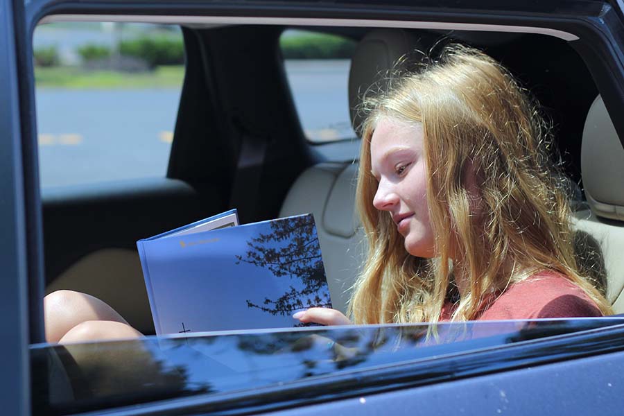 Libby Slaymaker, Class of '20 flips through her yearbook from her car after receiving it in the parking lot on Aug. 5. 