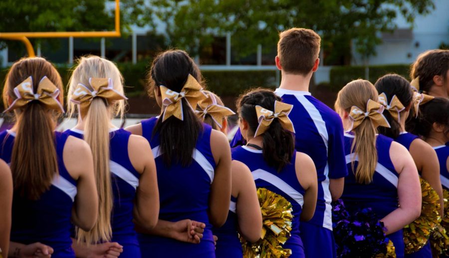 Cheerleaders line up for the National Anthem before the football game commences.