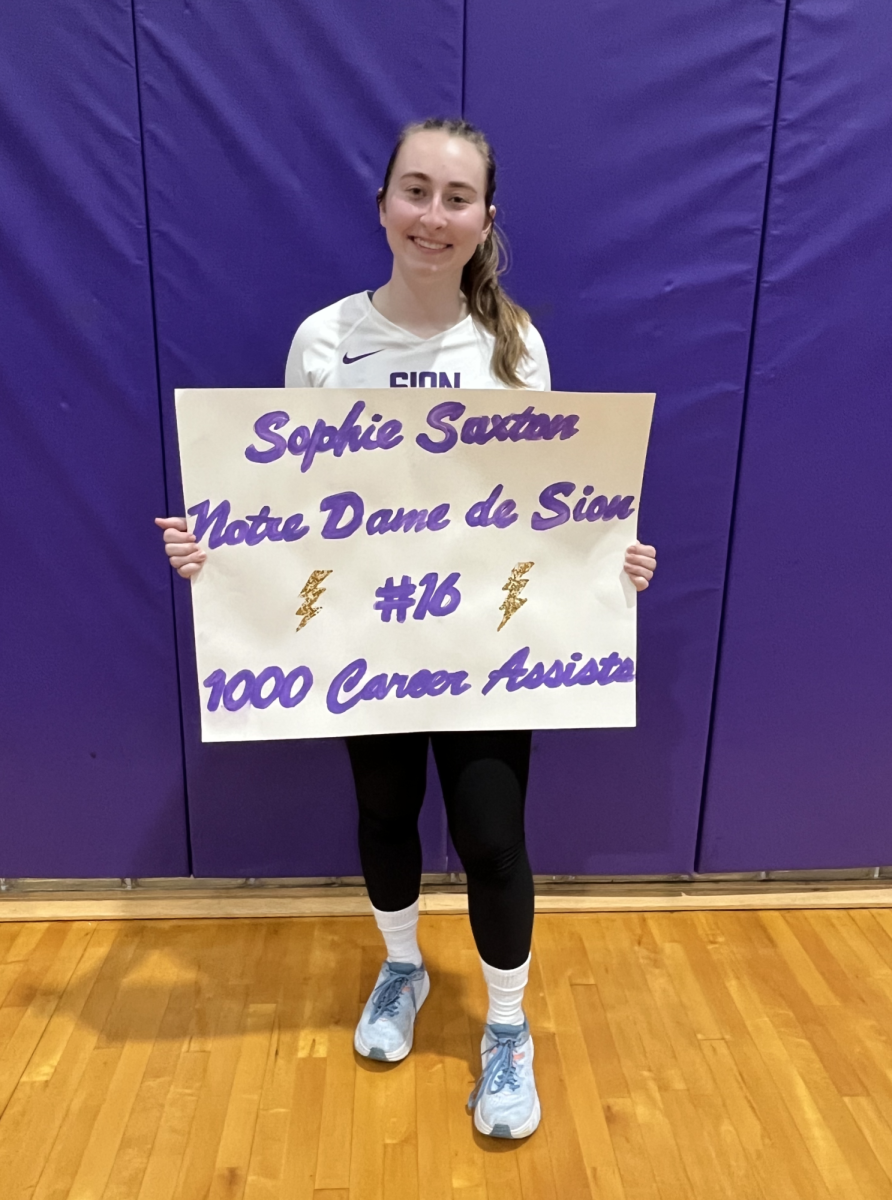 Standing with her mom’s homemade poster, senior Sophie Saxton takes a photo after the game. “We didn’t do much but take photos after the game,” Saxton said. “I got a lot of texts from coaches who couldn’t be there and from other schools.”