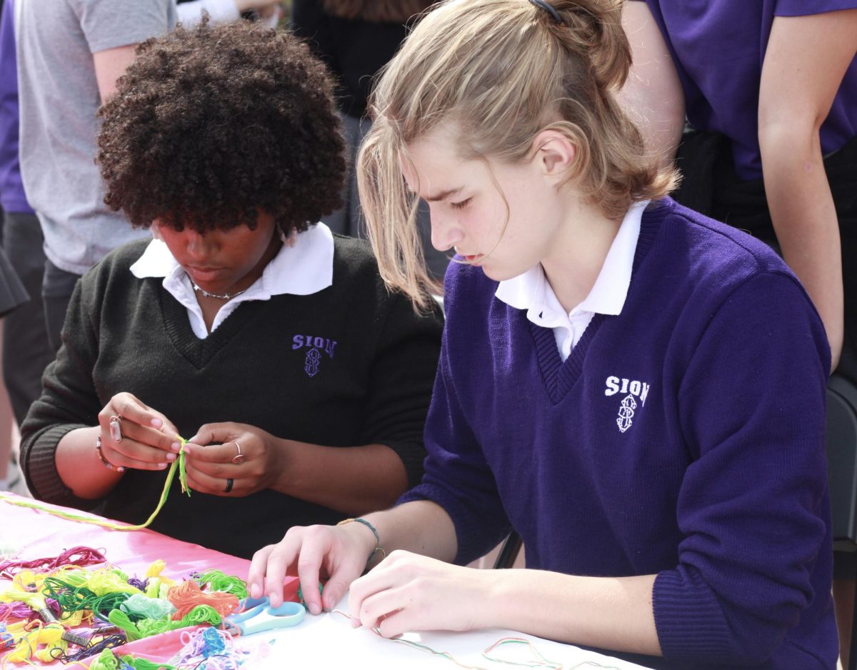 Freshmen Jae High and Neo Glennon work together to make a bracelet. The colorful string was provided by Spanish Club as a fun activity for the event.