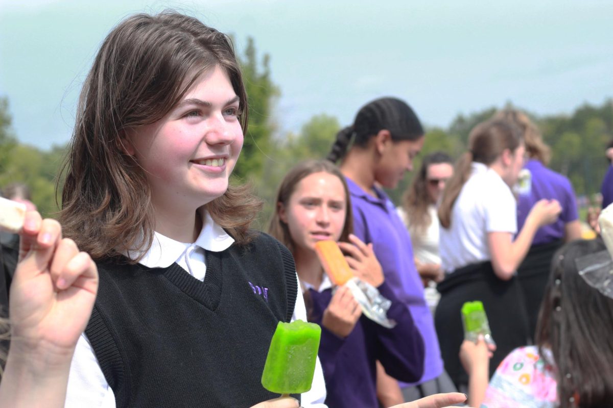 Junior Elwyn Patterson smiles as she converses with a friend and enjoys a lime popsicle. This year, each student received a popsicle as a part of the celebration.