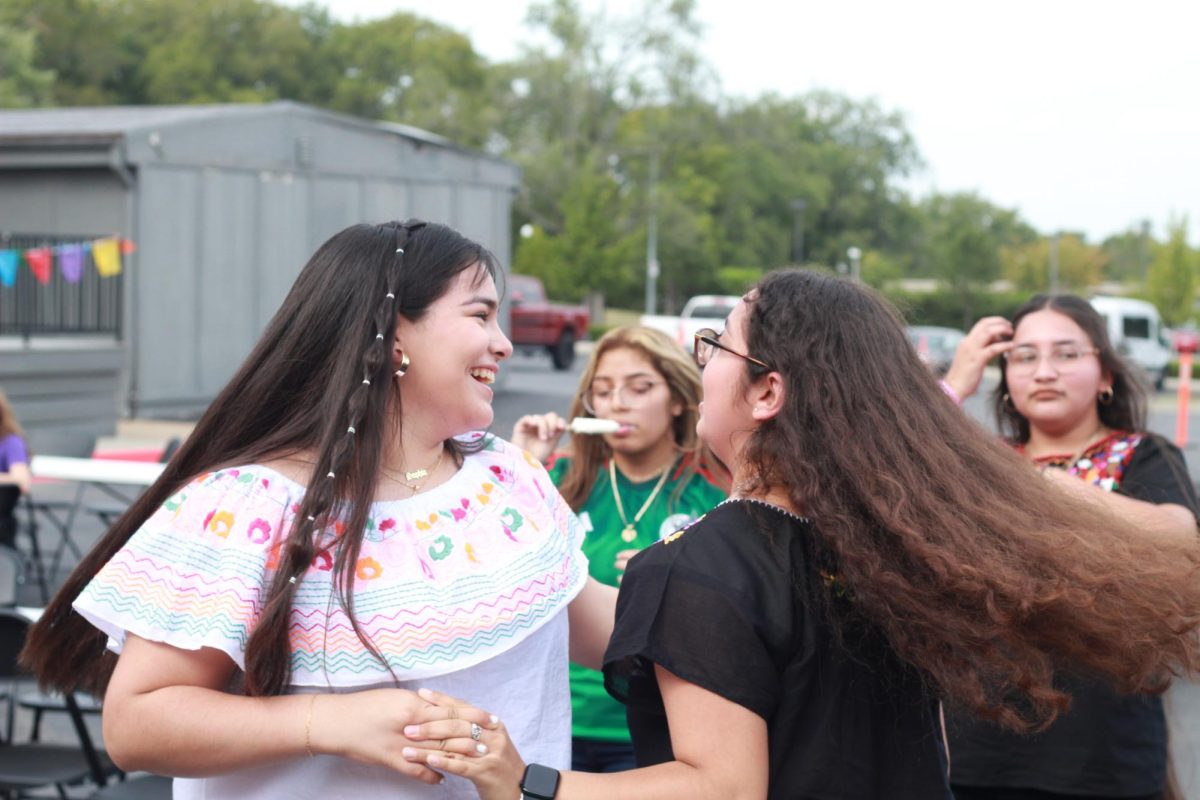 Sophomore Sophia De Lira spins with sophomore Wendy Castro, dancing along with the music. Both girls spent weeks working together in the Spanish for Heritage Speakers class to help make the celebration possible.