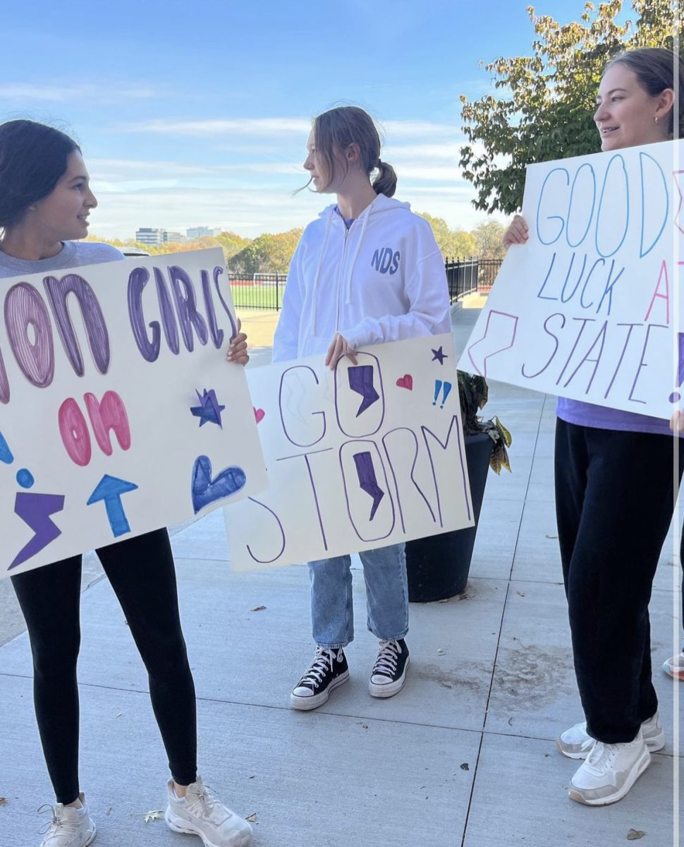 Holding up their signs, students cheer on their cross country friends who will be competing on November 3.