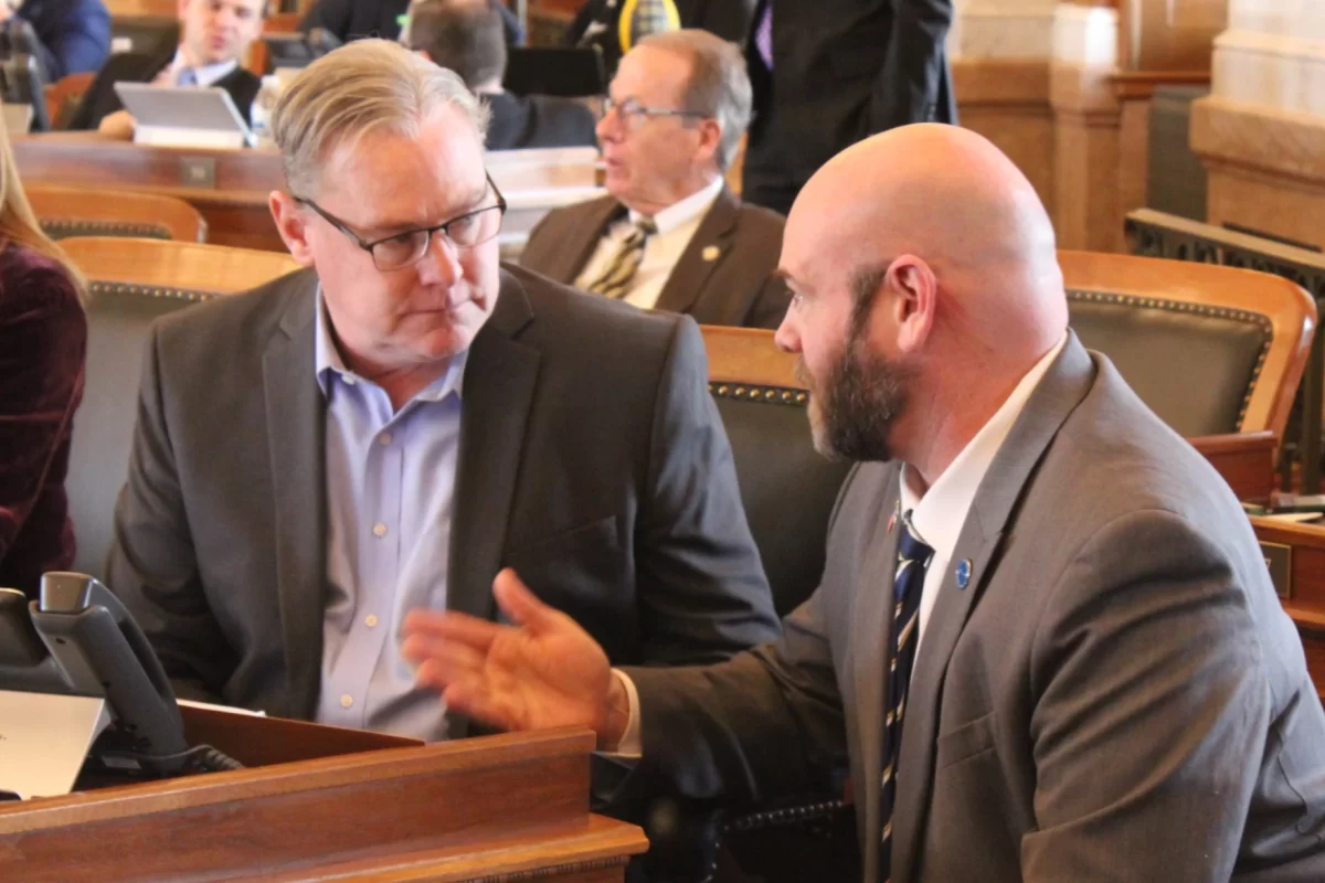 Representatives Sean Tarwater (left) and Stephen Owens (right) consult each other Thursday in the House of Representatives before discussion the tax reform bill. The bill passed 81-37 in the House before being vetoed by Governor Laura Kelly. (NPR)
